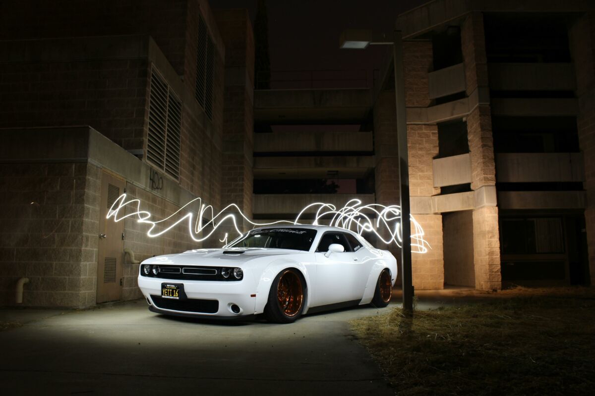 Home 7 White luxury sports car parked with dynamic light trails at night against a building backdrop.